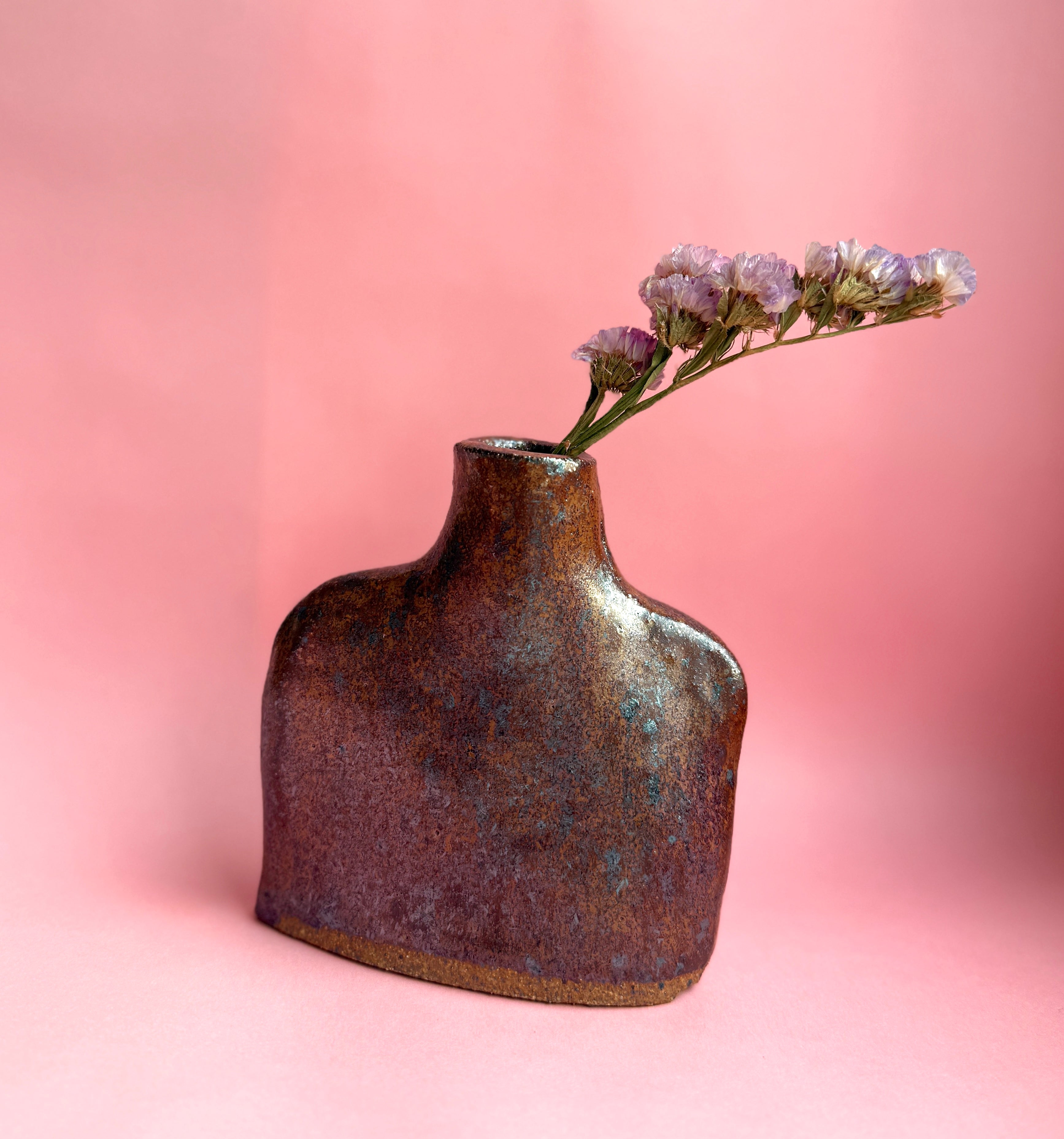 Ceramic vase with a single flower on a pink background