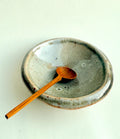 Ceramic bowl with wooden spoon on a light background