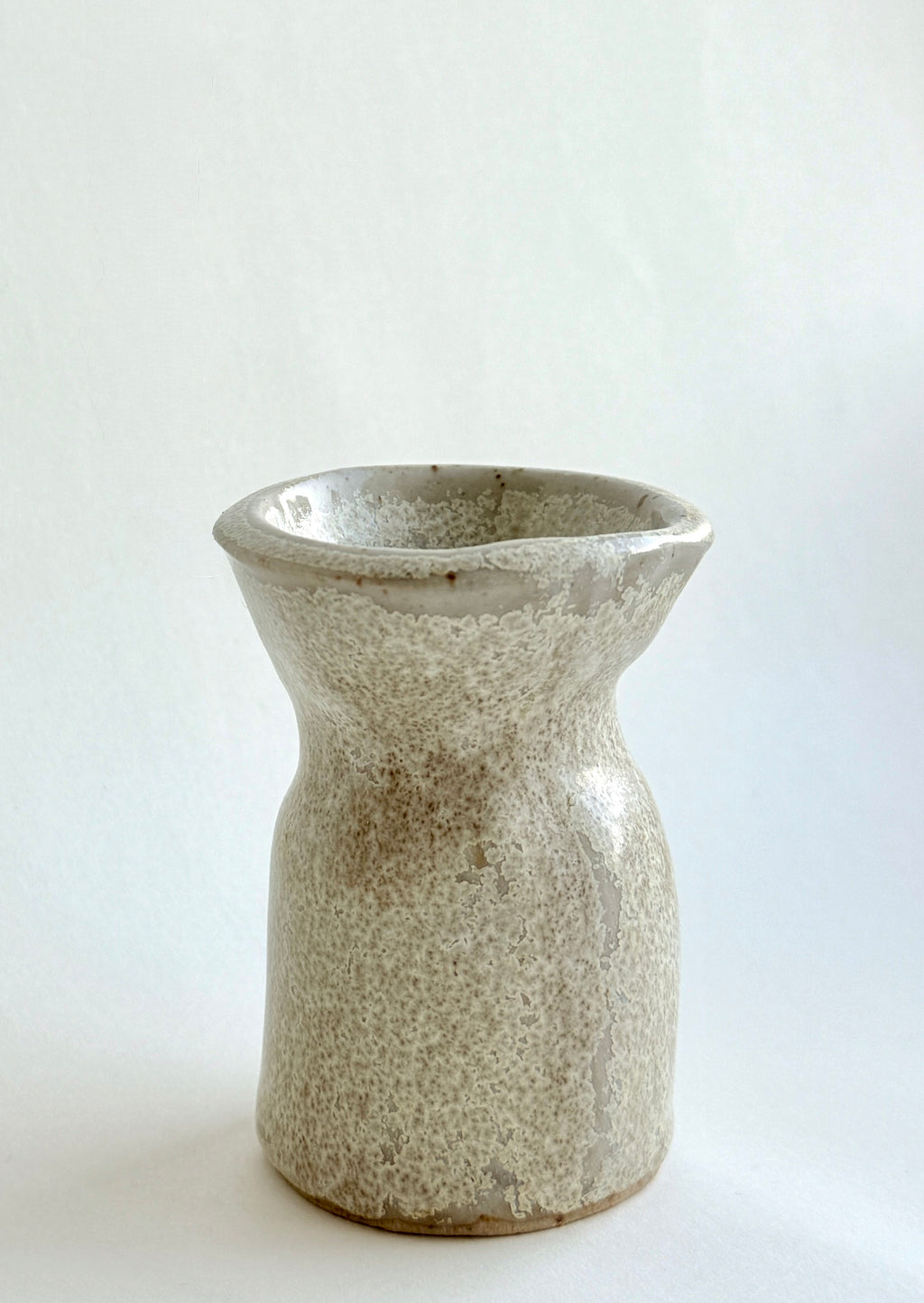 Handbuilt stone-textured ceramic mini vase with mottled beige and grey glaze and soft hourglass shape