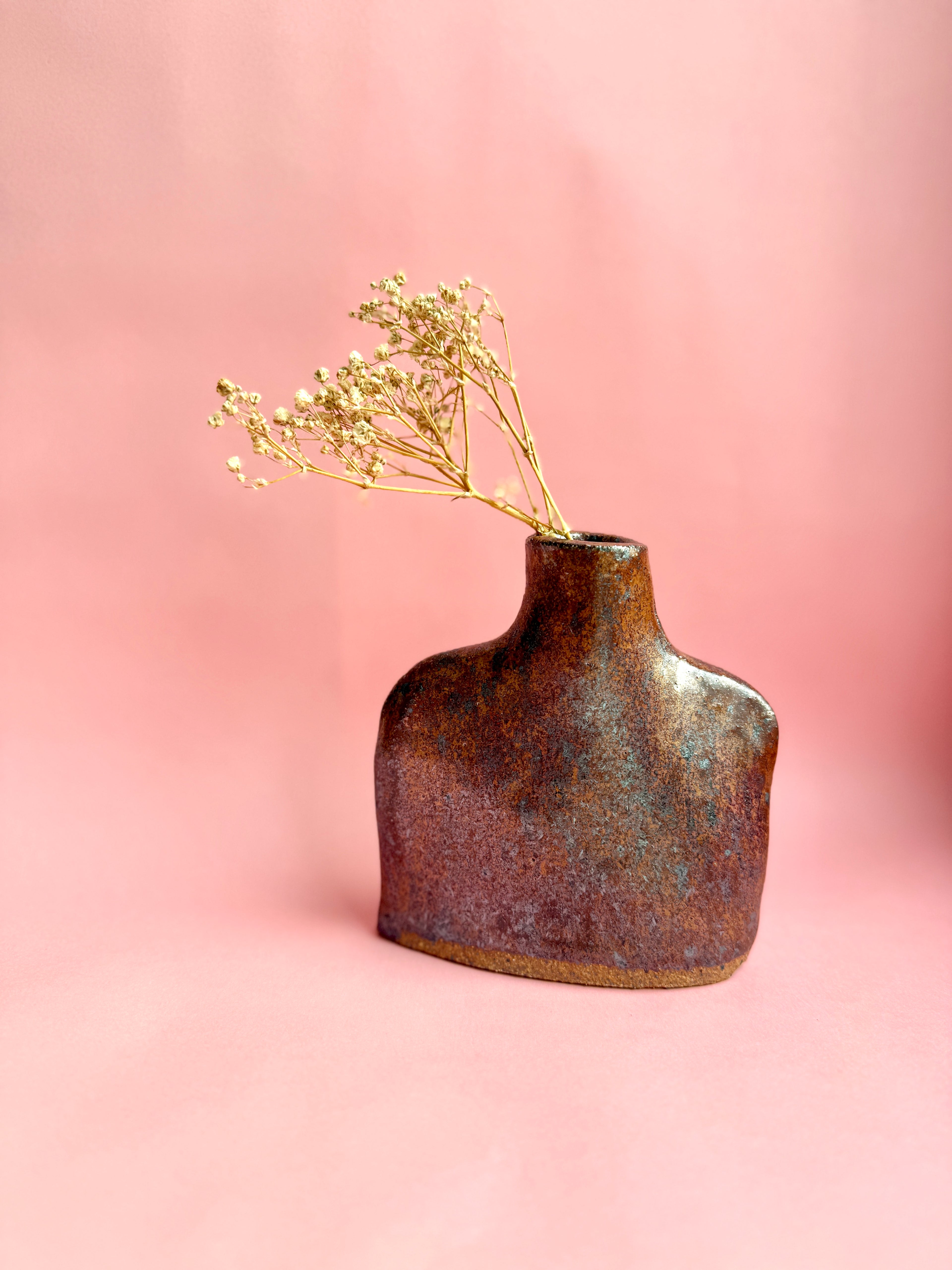 Ceramic vase with dried flowers on a pink background