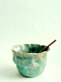 Turquoise ceramic bowl with a wooden spoon on a white background