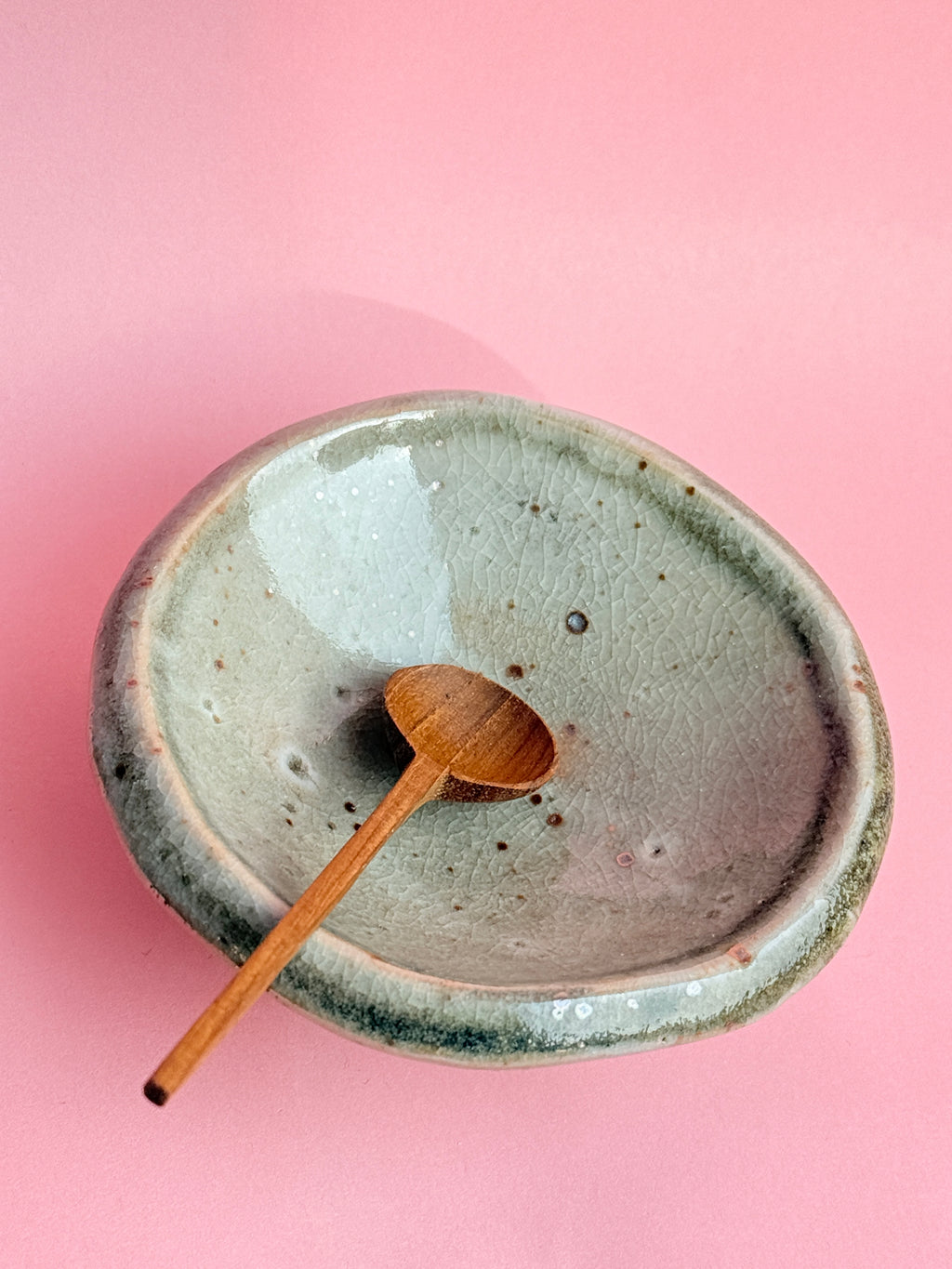Ceramic bowl with wooden spoon on a pink background