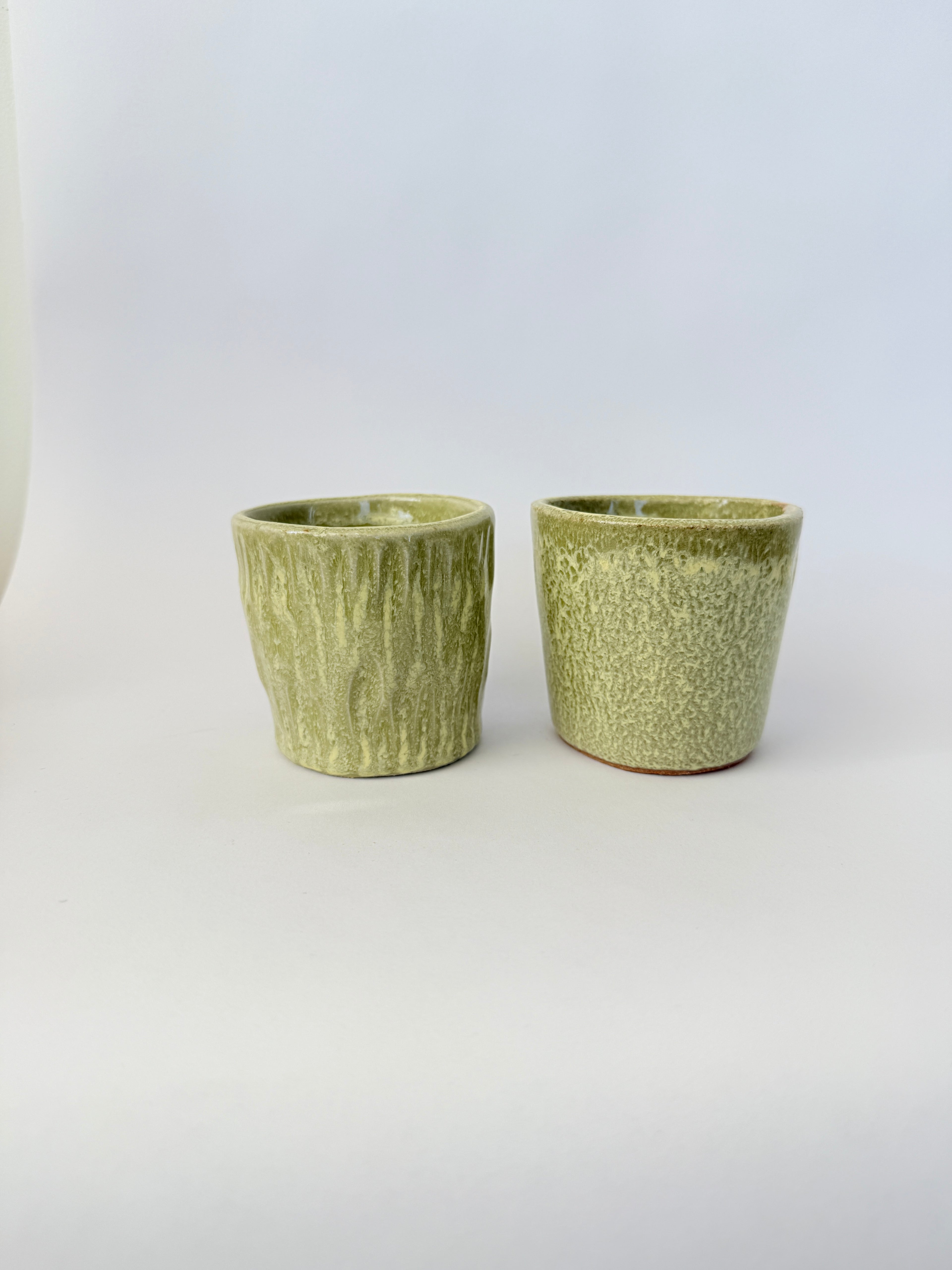 Two green metallic cups on a white background