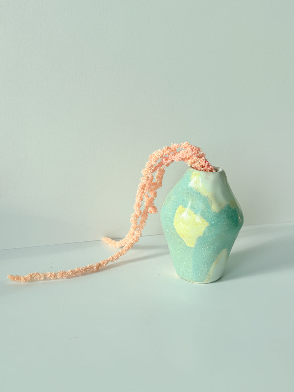 Handbuilt ceramic bud vase in blue and butter yellow holding a peach dried amaranth stem, made in NYC by Bunzy NYC
