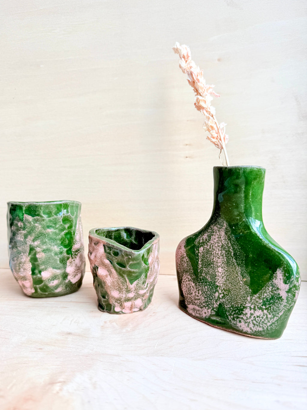 Three green ceramic vases with marbled patterns on a light background