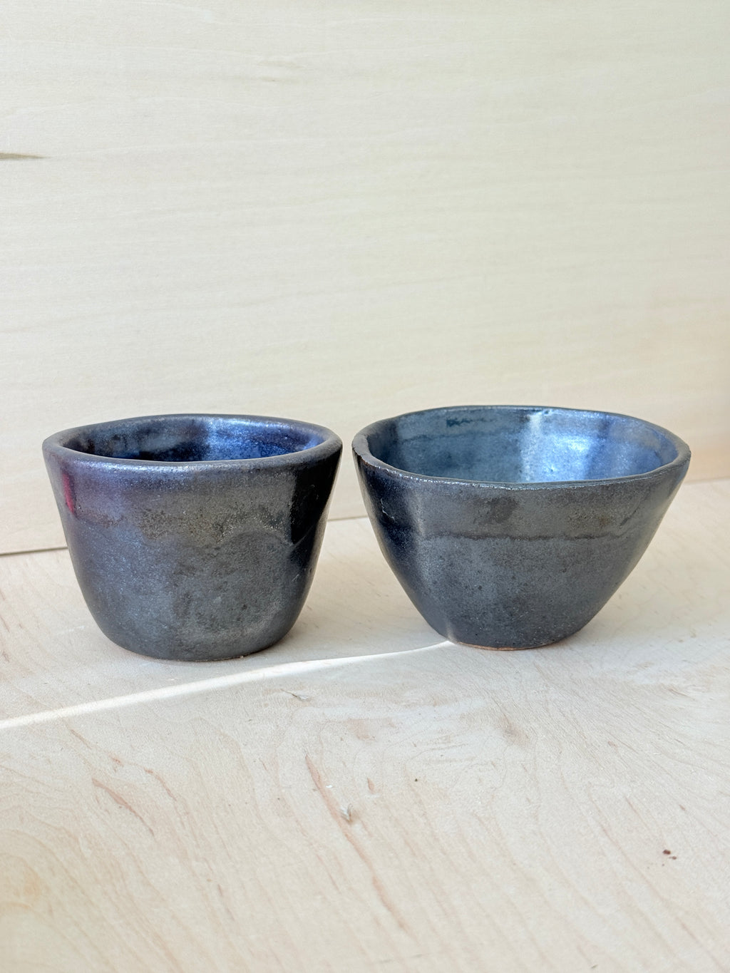 Two metallic cups on a light wooden surface