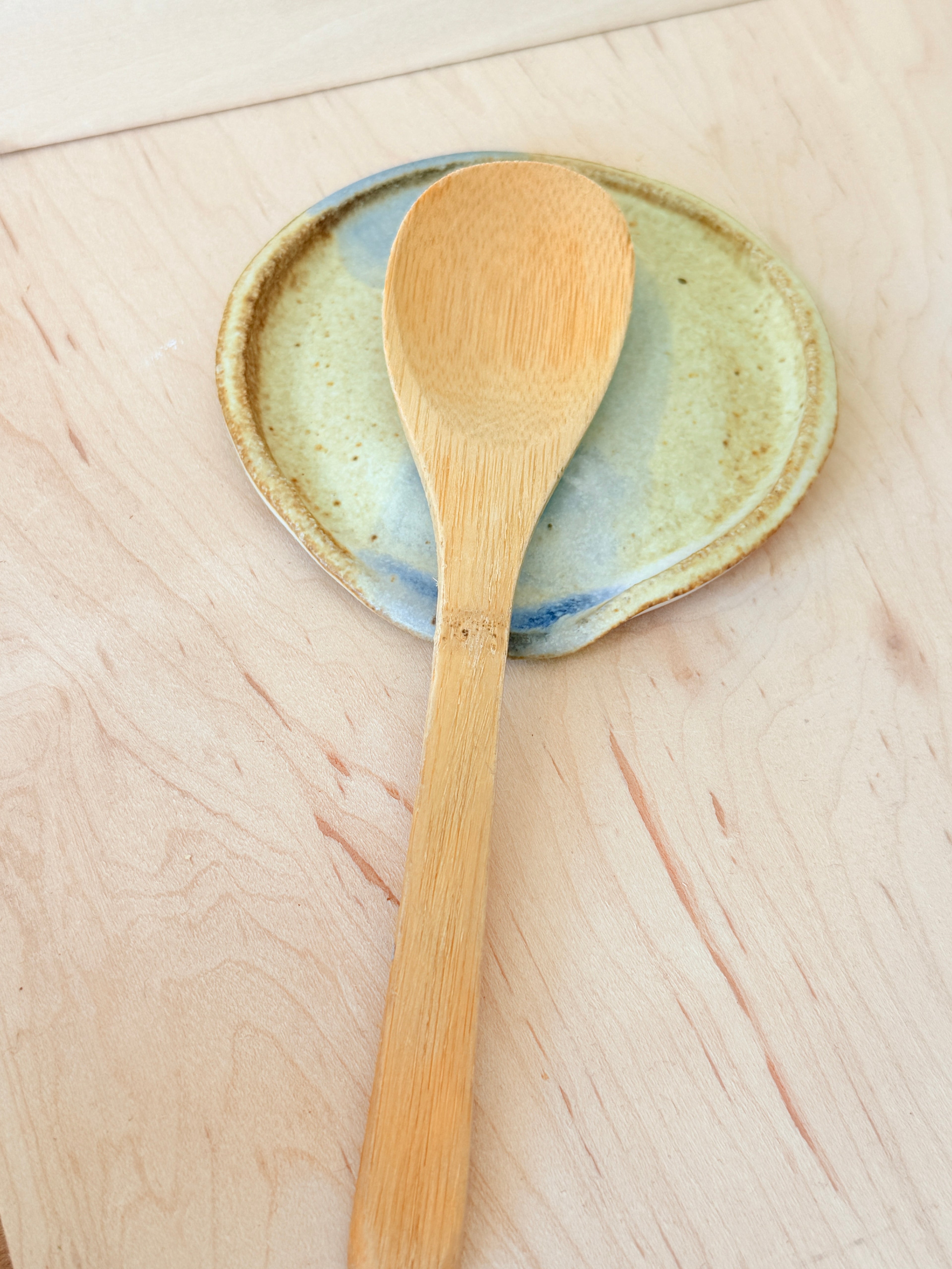 Wooden spoon on a ceramic plate with a light wood background