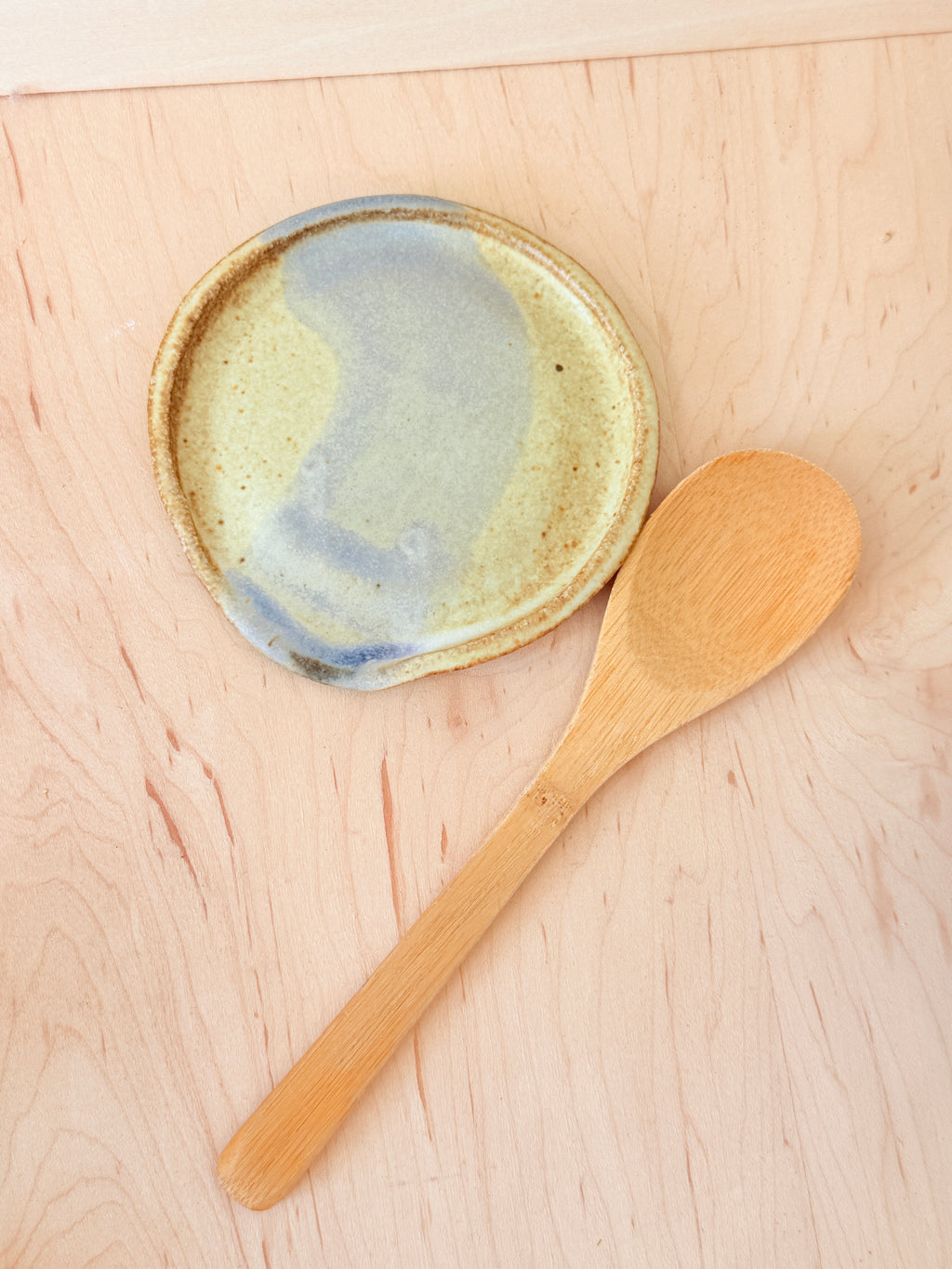 Ceramic dish with blue glaze and wooden spoon on a wooden surface