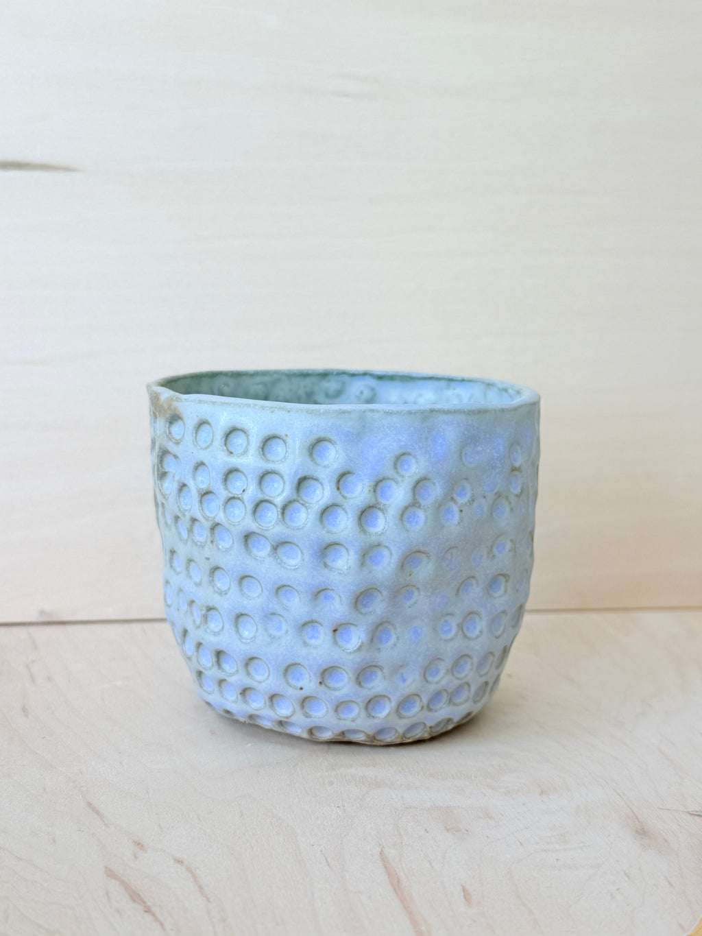 Ceramic pot with a textured surface on a light wooden surface
