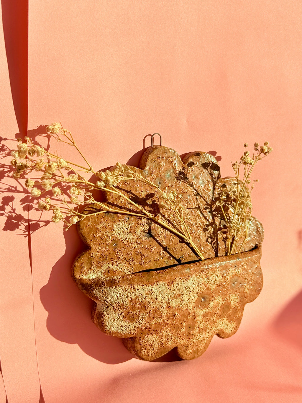 Close-up of textured handmade ceramic wall pocket with natural speckled glaze
