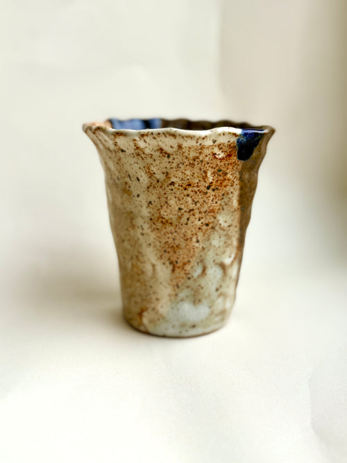 Hand-built stoneware cup with creamy speckled glaze and subtle blue