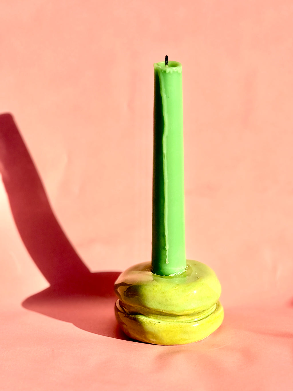 Green candle on a lime green candlestick against a pink background