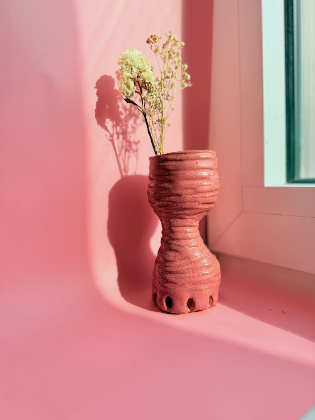 Ceramic vase with dried flowers on a pink wall