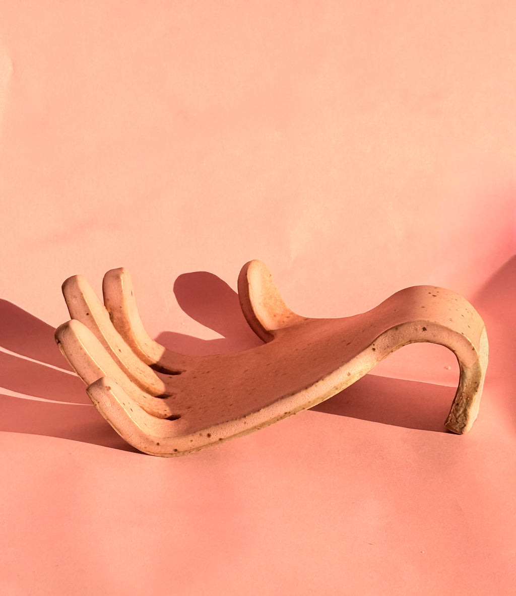 Handbuilt stoneware sponge holder in soft pink speckled clay on pink background