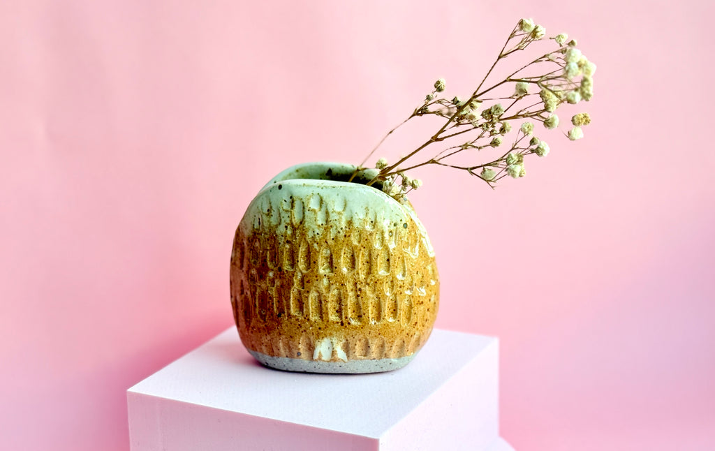 Handbuilt ceramic mini vase with speckled stoneware glaze holding dried florals