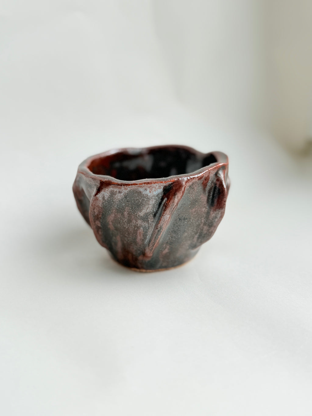 Hand-built stoneware cup with earthy brown glaze, organic shape, 