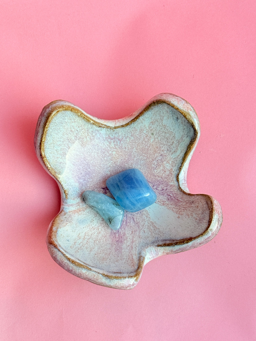 Handmade ceramic ring dish with pastel glaze holding small stones