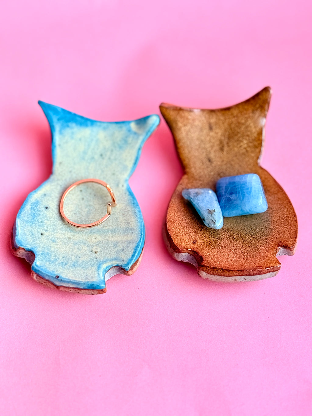 Two ceramic vases with blue and brown glazes on a pink background