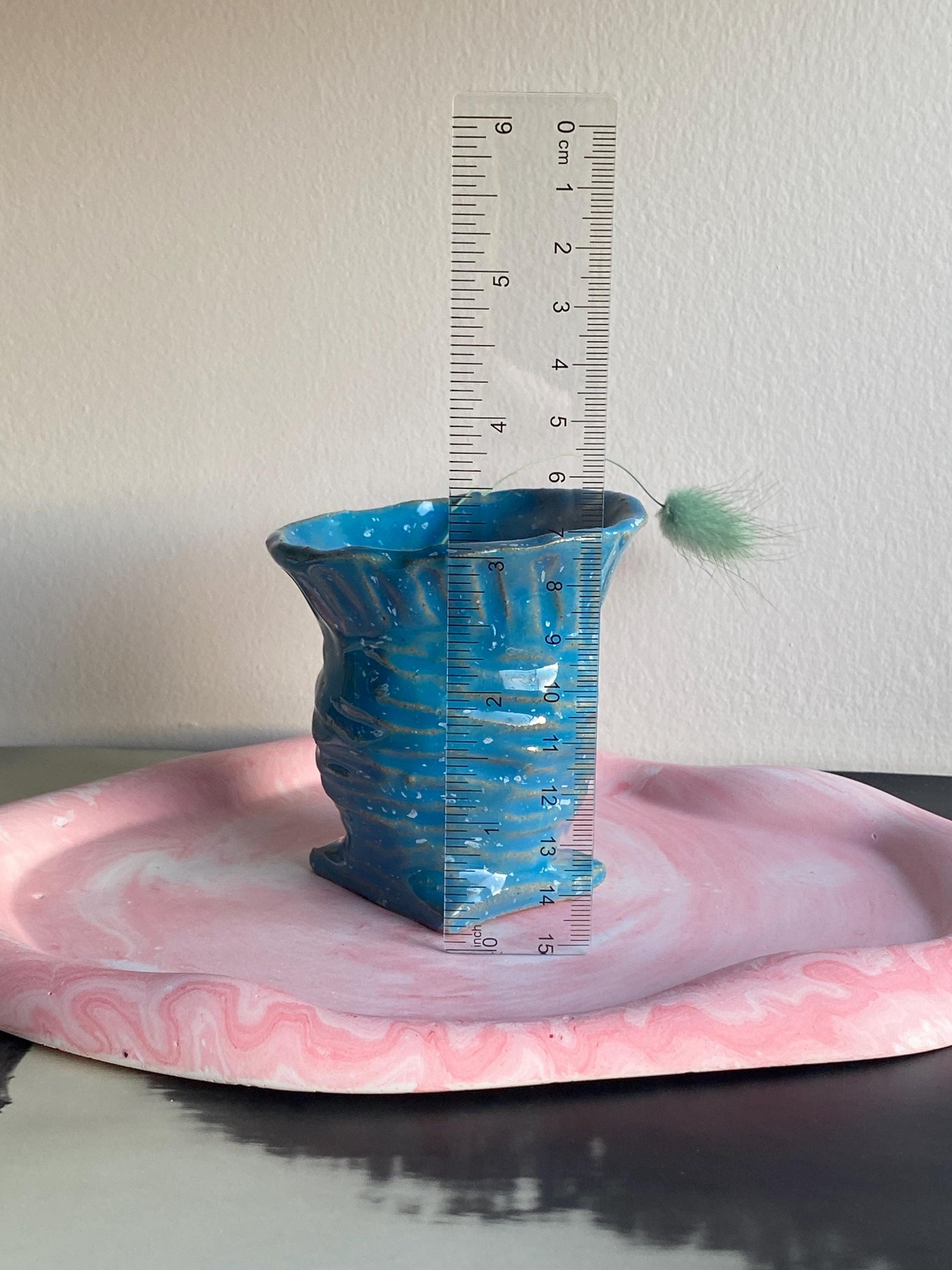 Small blue speckled ceramic vase, perfect for displaying flowers or as a decorative accent piece in modern home decor. Pictured with ruler for scale.