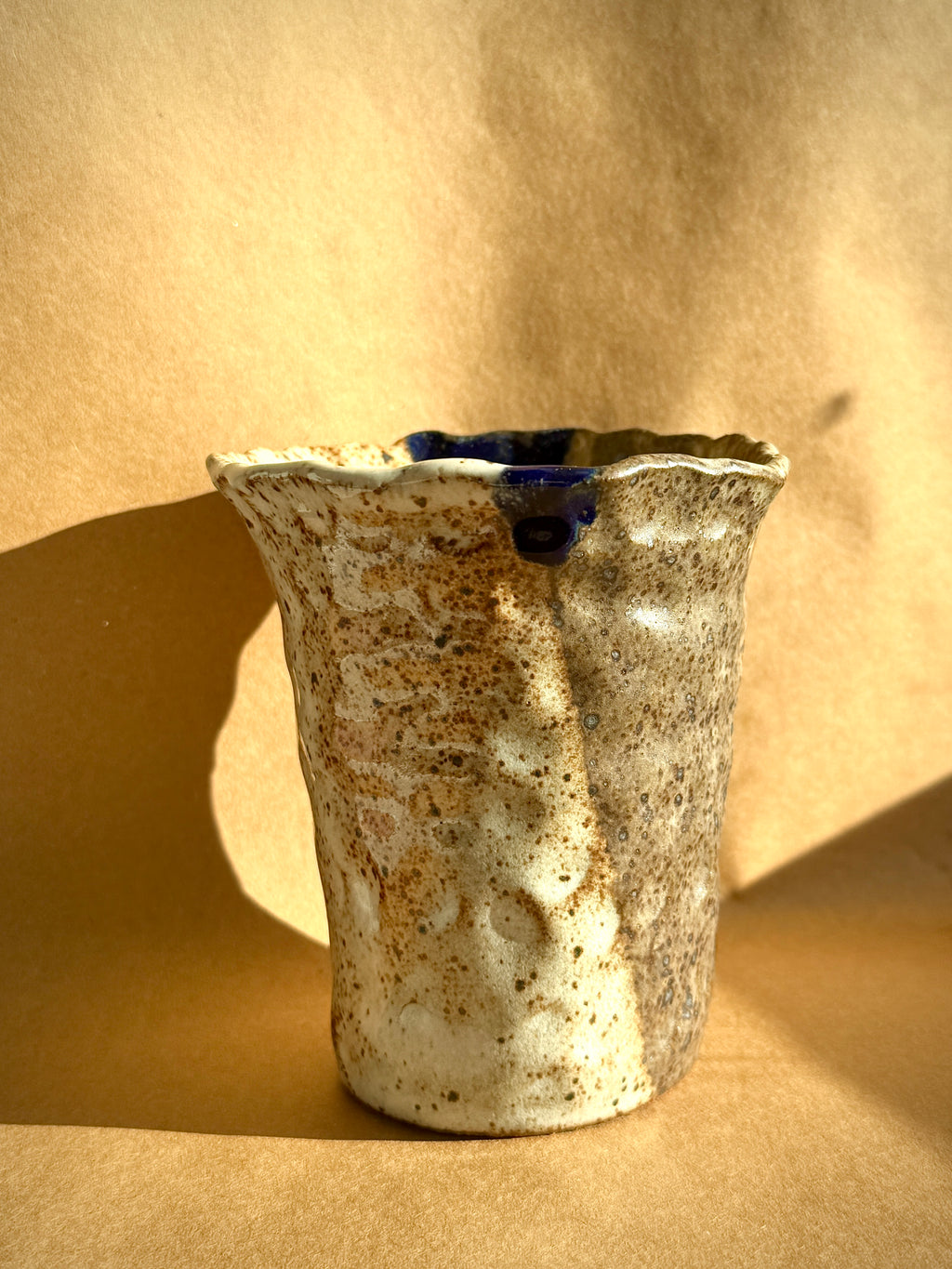 Hand-built stoneware cup with creamy speckled glaze and subtle blue