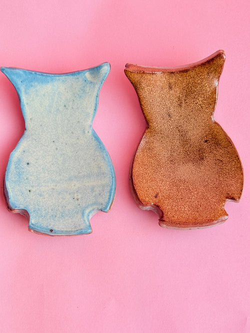 Two ceramic vases, one blue and one brown, on a pink background