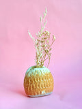 Ceramic vase with textured surface and dried plants on a pink background