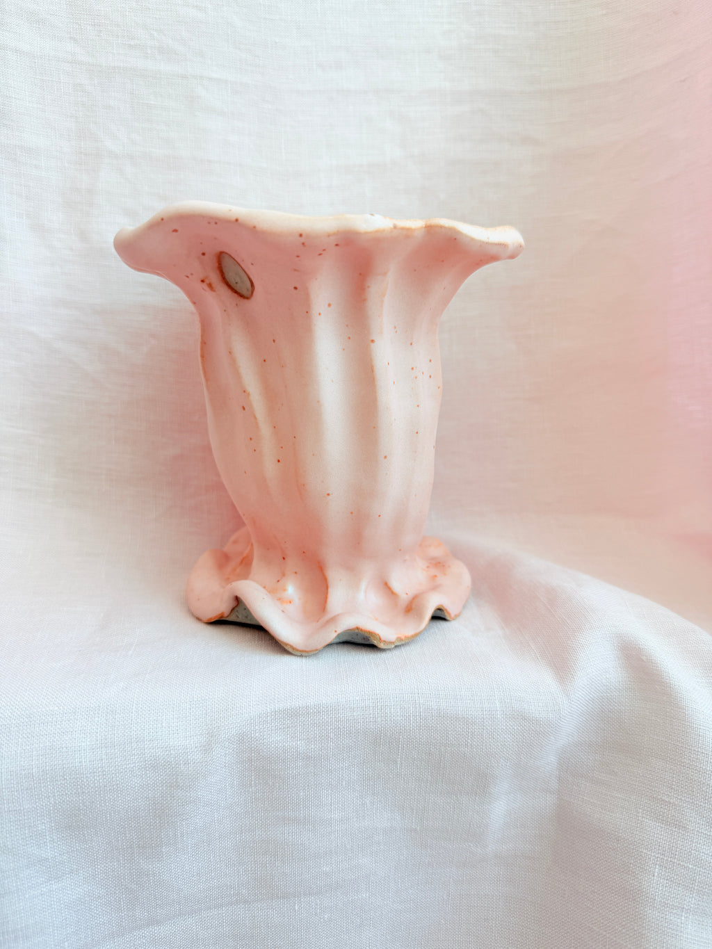 Pink ceramic flower-shaped object on a white fabric background