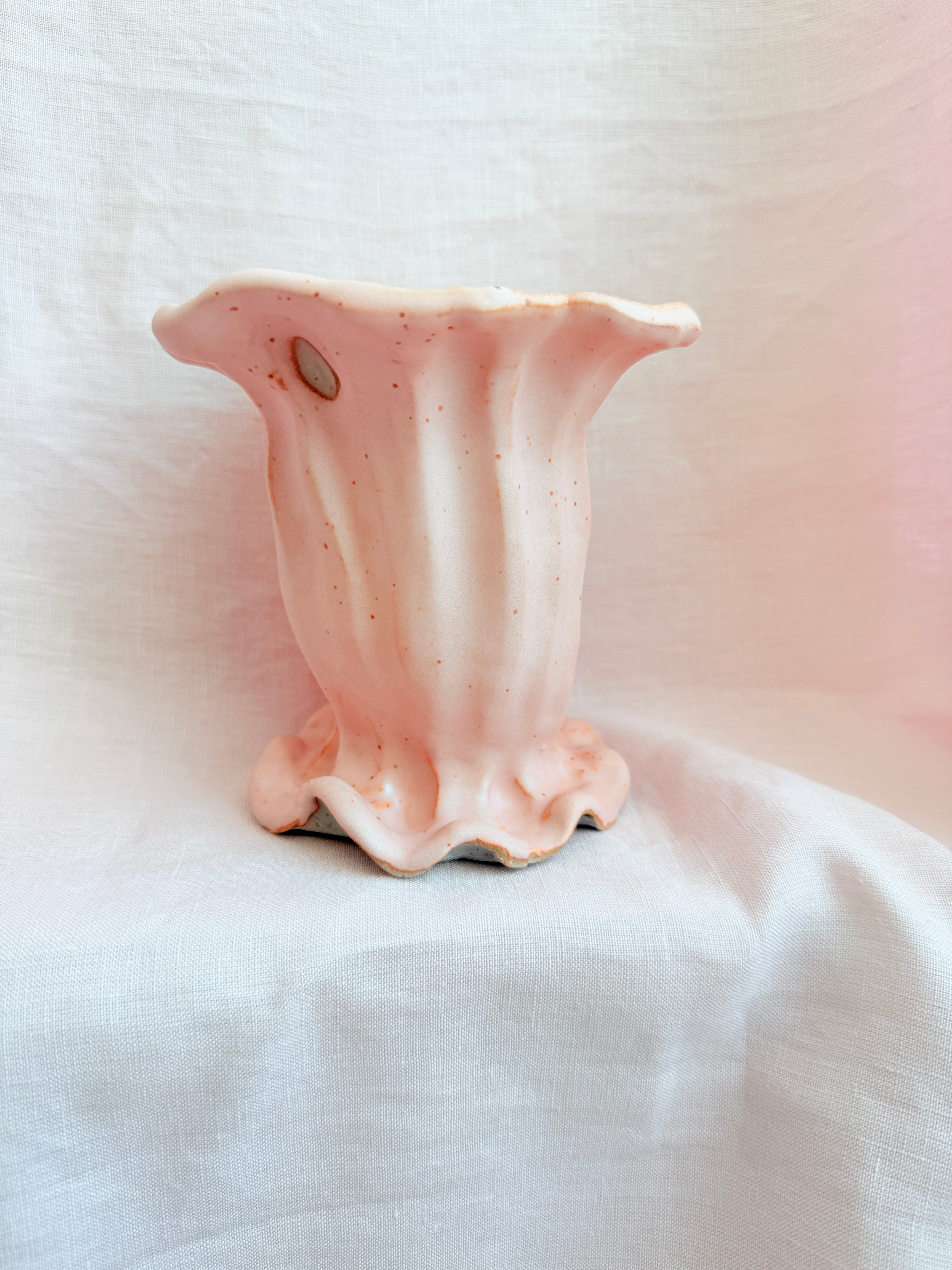 Pink ceramic flower-shaped object on a white fabric background